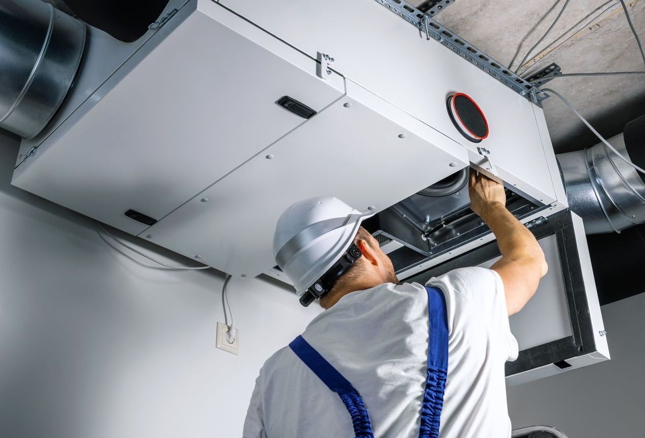 A man is working on a ventilation system in a building.