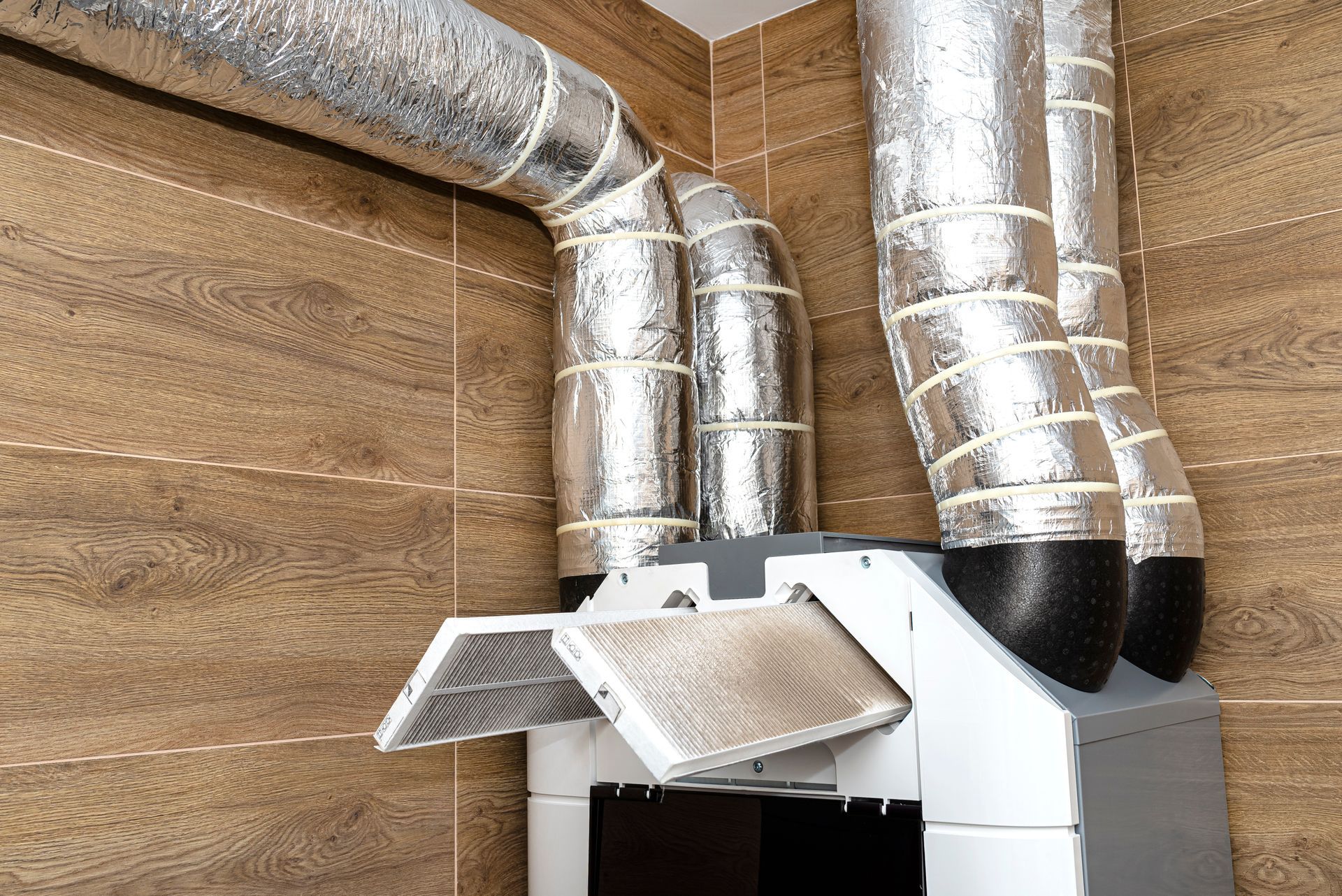 A kitchen hood with a lot of pipes coming out of it.