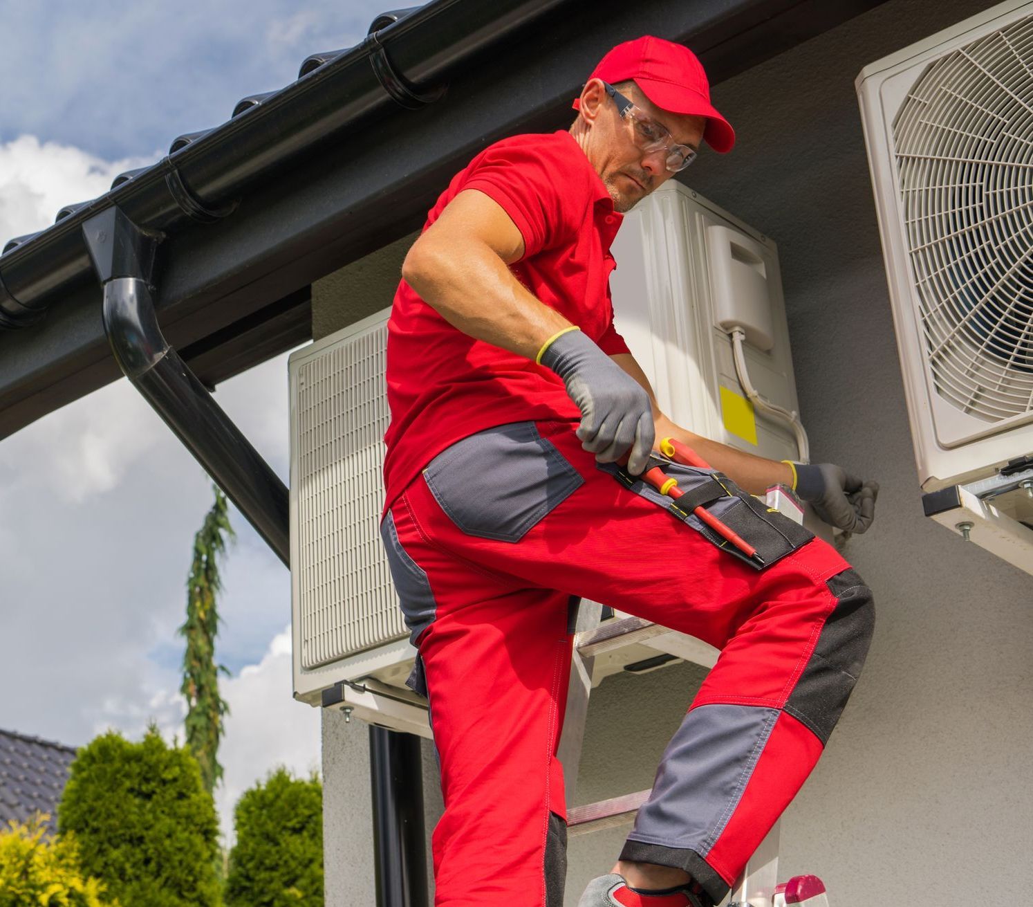 A man is working on an air conditioner on the side of a house.