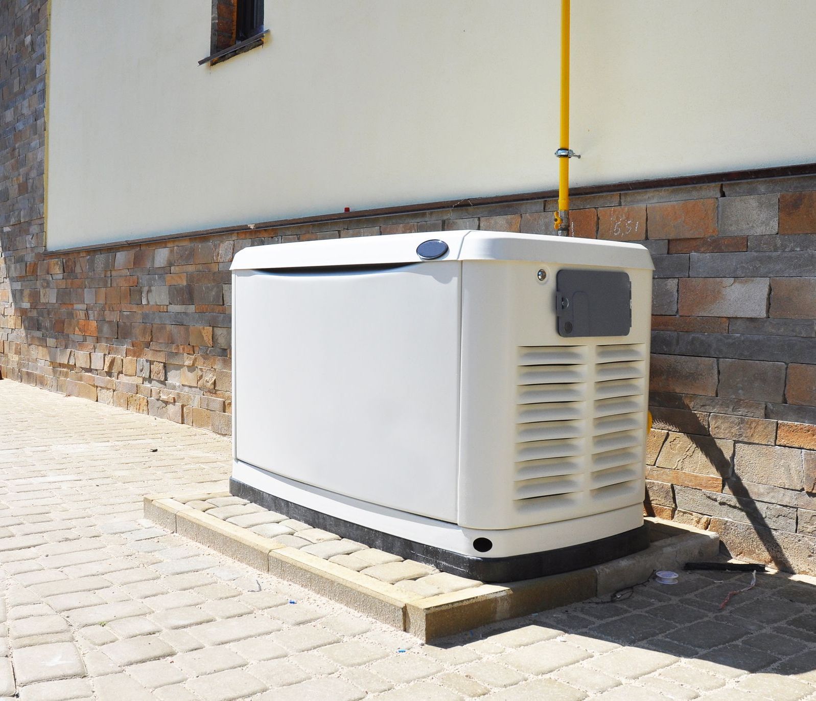 A white generator is sitting on the side of a house.