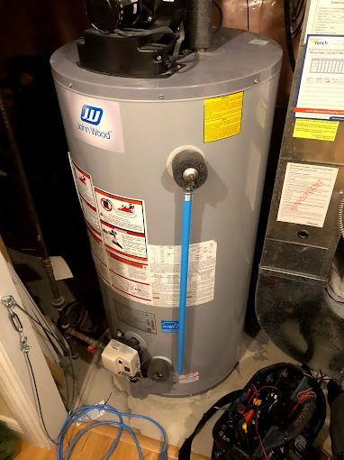 A water heater is sitting on a wooden floor in a room.