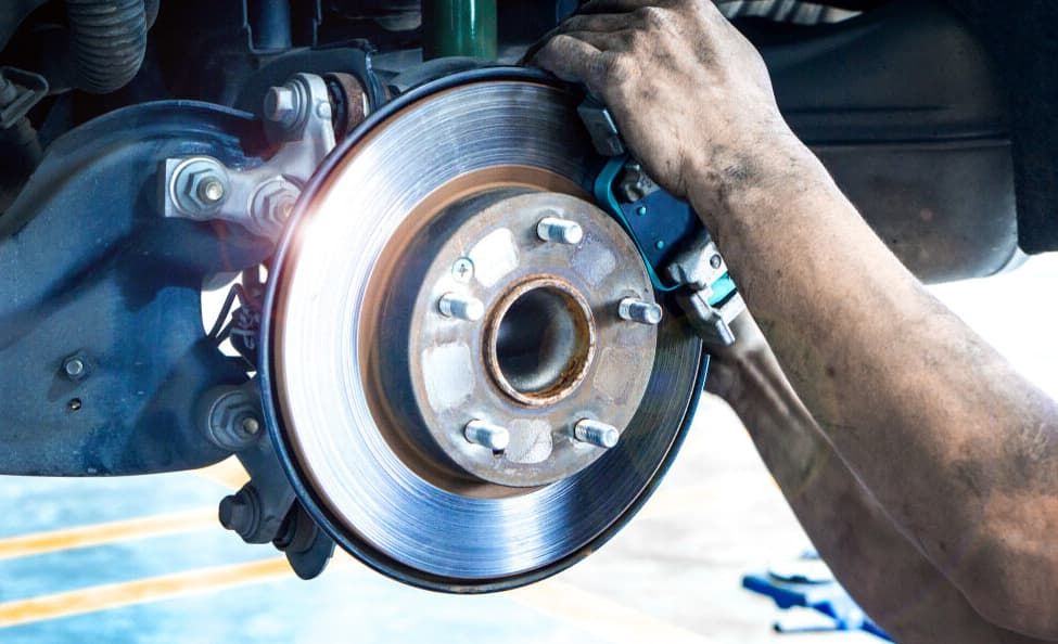 White Car With Red Brake Calipers And Rotor, Front Tire Removed, In A Shop — MC Automotive Service & Repairs in Maitland, NSW