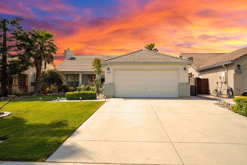 House exterior with a driveway and vibrant sunset sky.