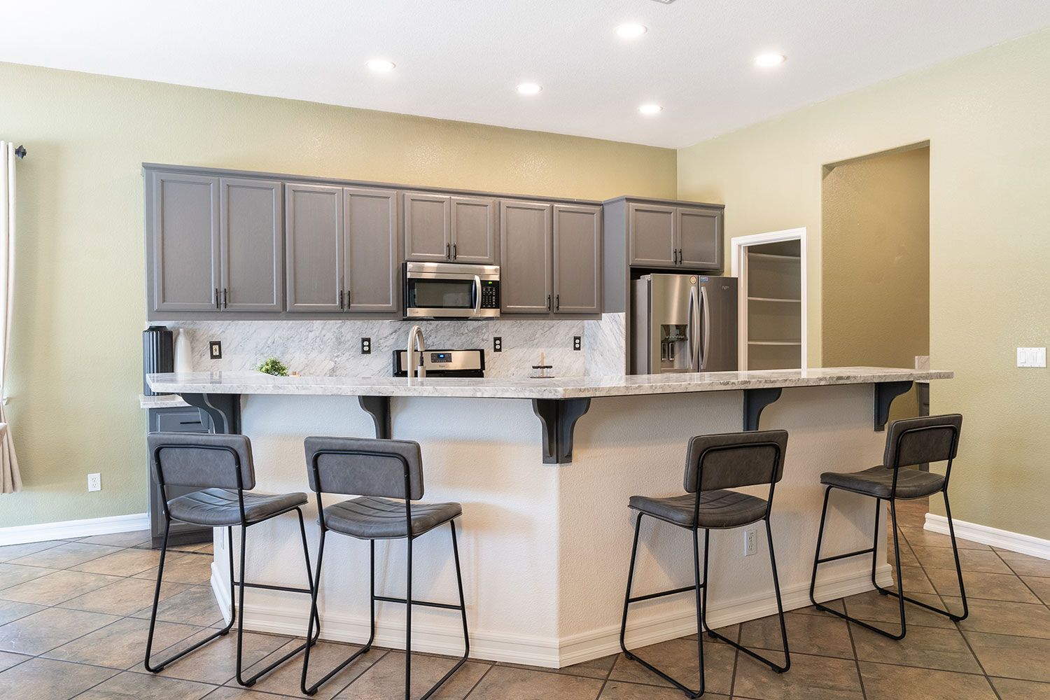 Gray kitchen with counter and bar stools; stainless steel appliances.