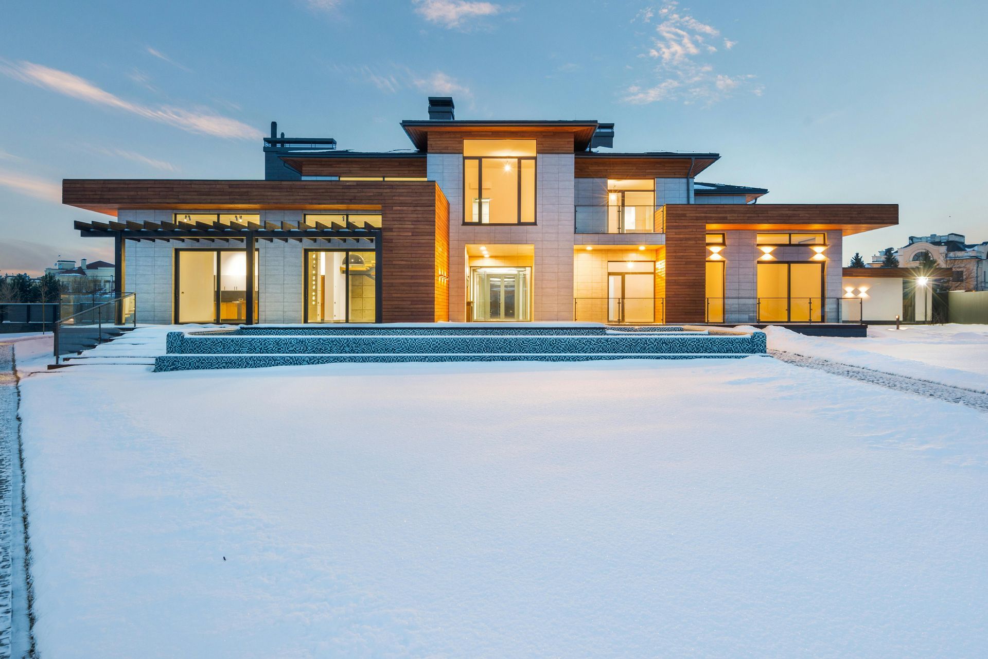 Modern house with wooden accents and large windows on a snowy landscape.