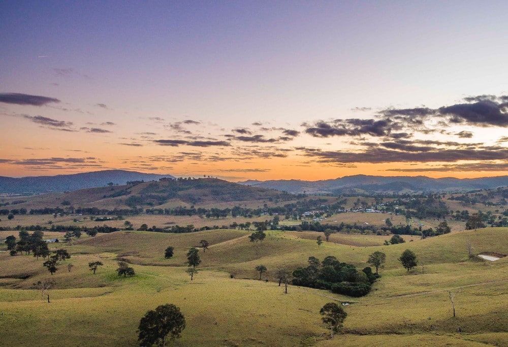 A Sunset Over a Field with Trees and Mountains in The Background — Acres 2 Mow in Maitland, NSW