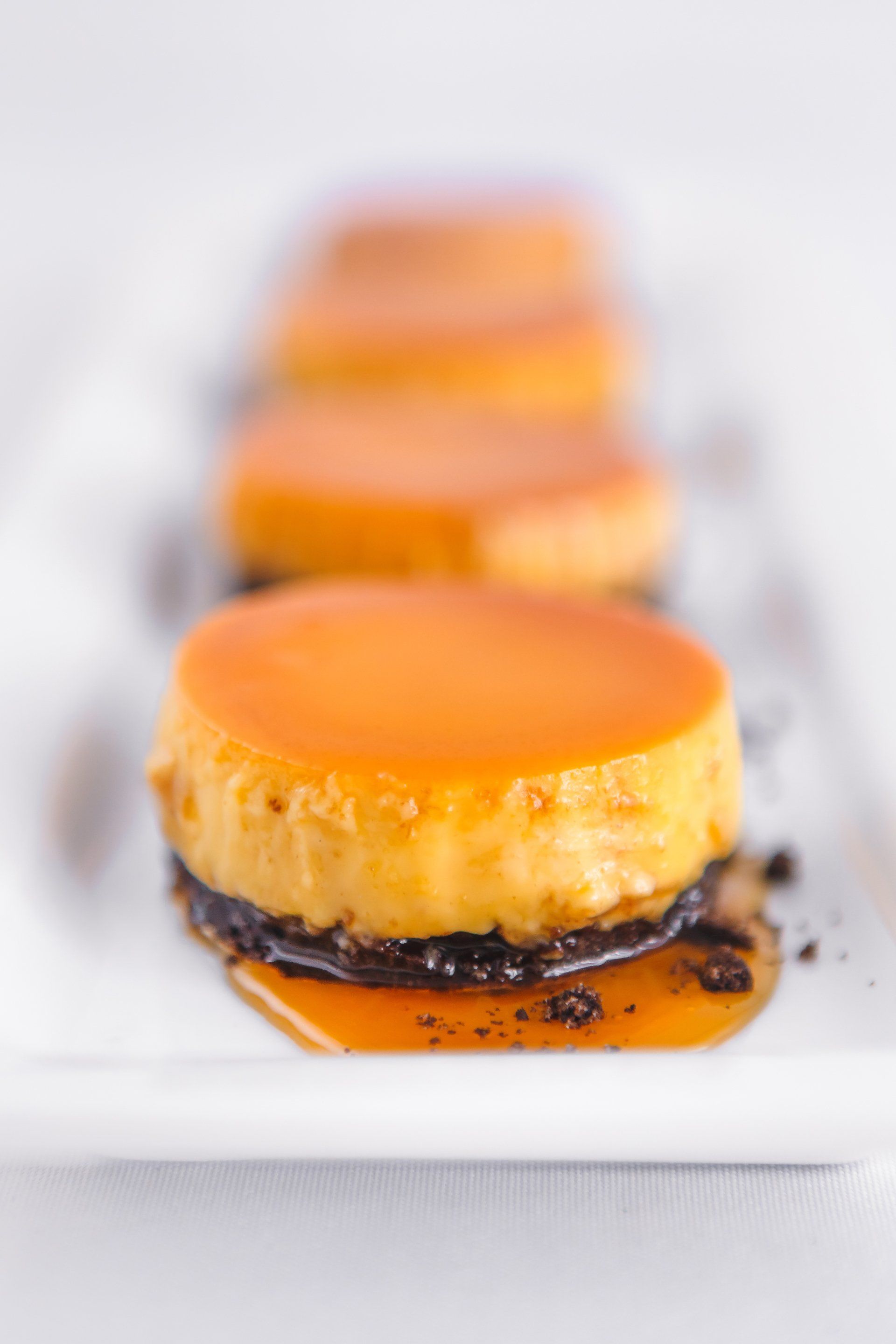 flan on top of an oreo cookie crust  and caramel drizzle on a white platter