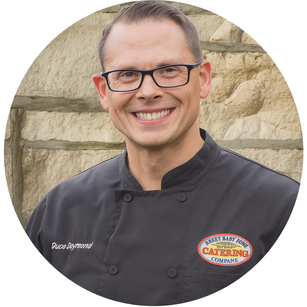 A man wearing a black chef 's jacket with a name and logo on it
