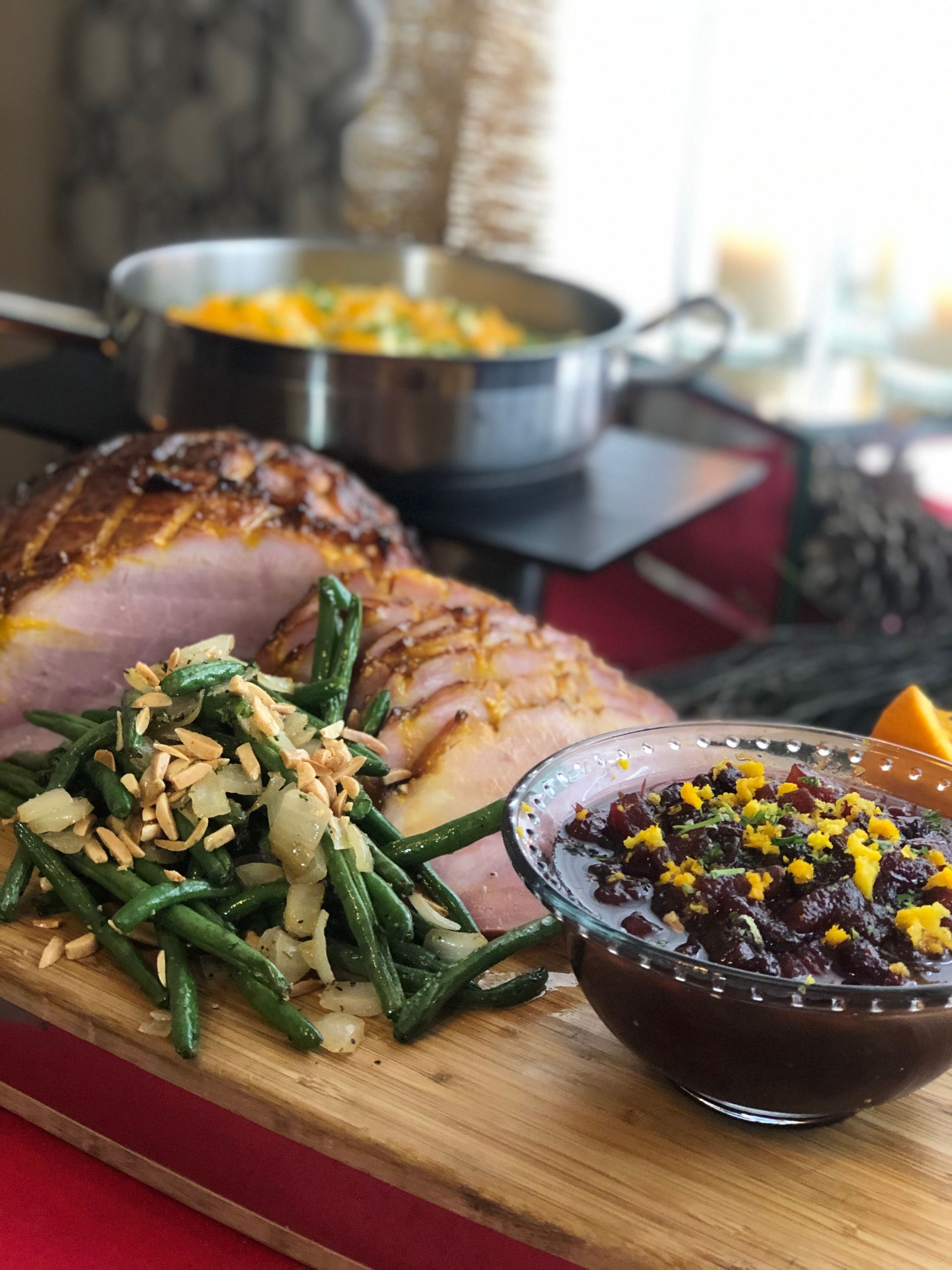 ham, green beans and cranberry sauce on a wood platter.