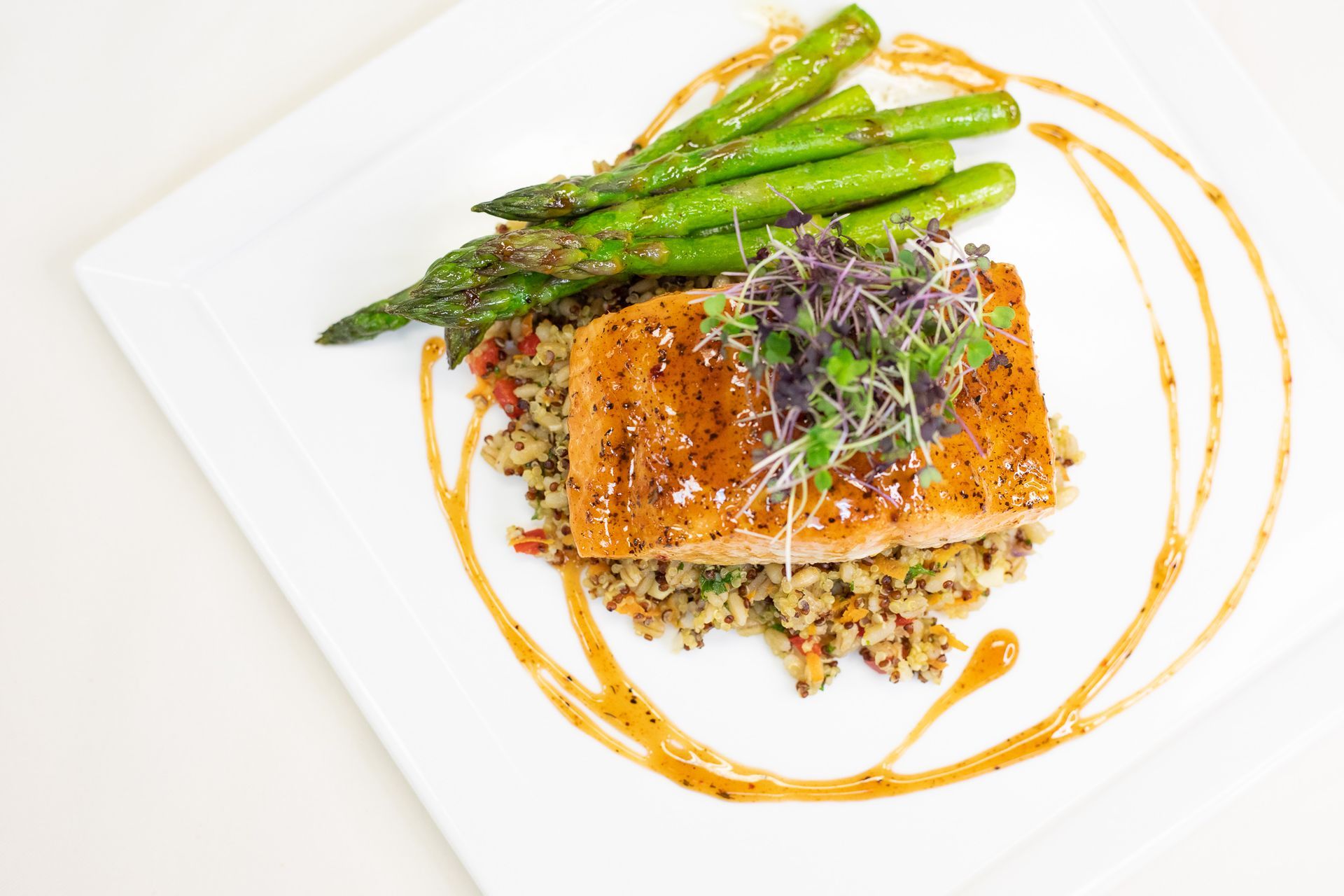 a plate with salmon, grains, and asparagus.
