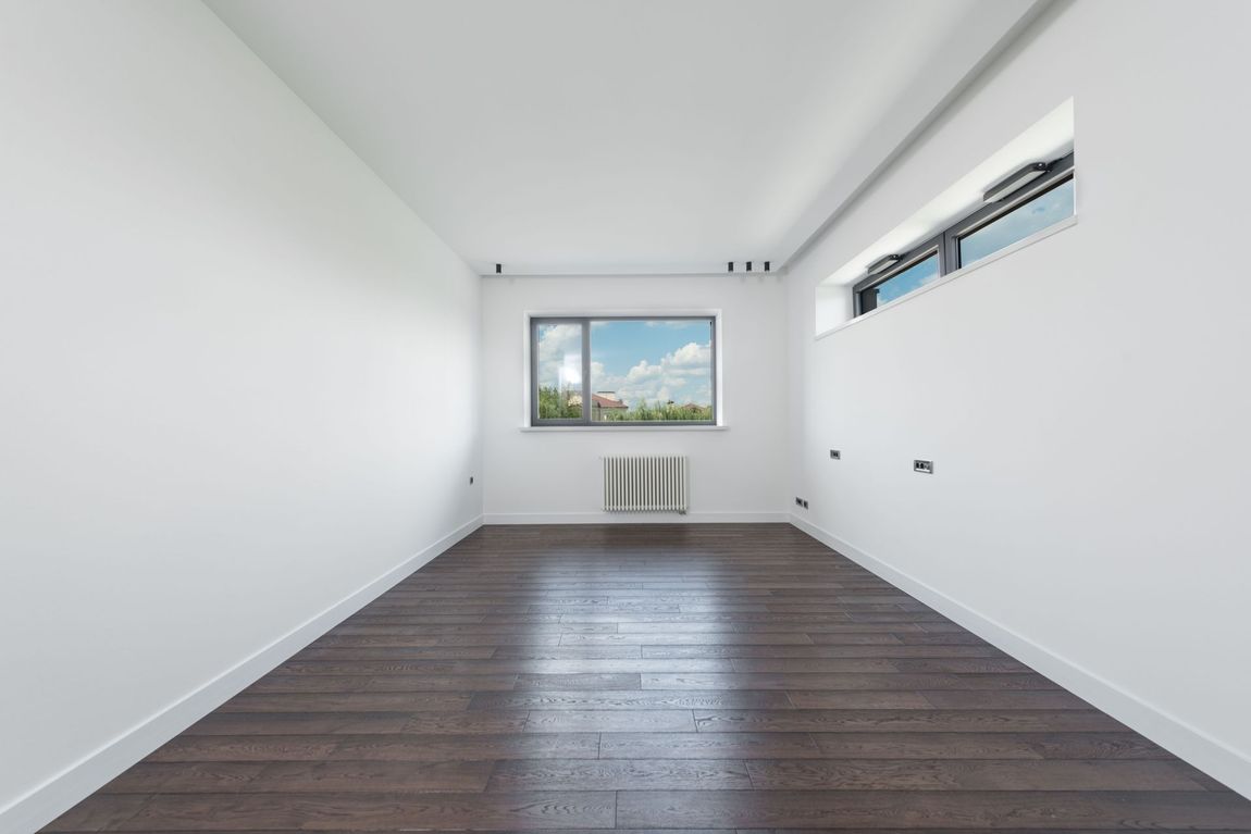 Converted garage functioning as a home office with large window and concrete flooring
