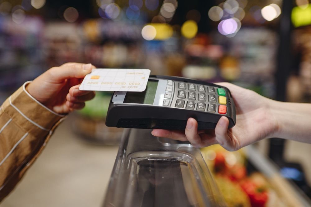 Person paying with a credit card at a checkout terminal.
