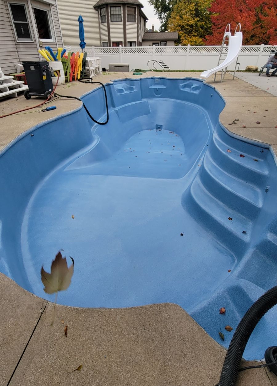 A blue swimming pool with a slide in the backyard.