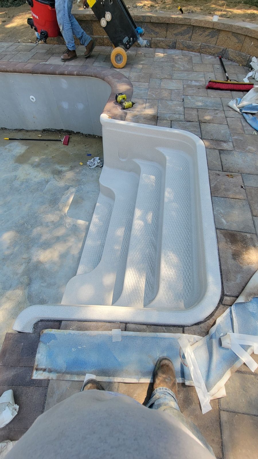 A person is standing next to a staircase that is being built into a pool.
