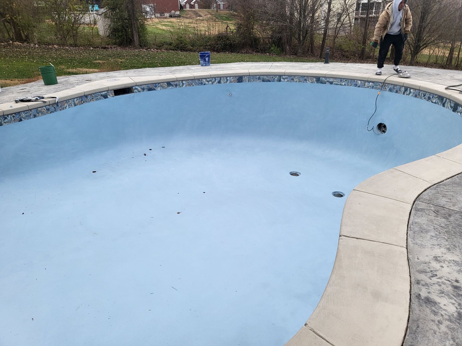 A man is standing on the edge of a large swimming pool.