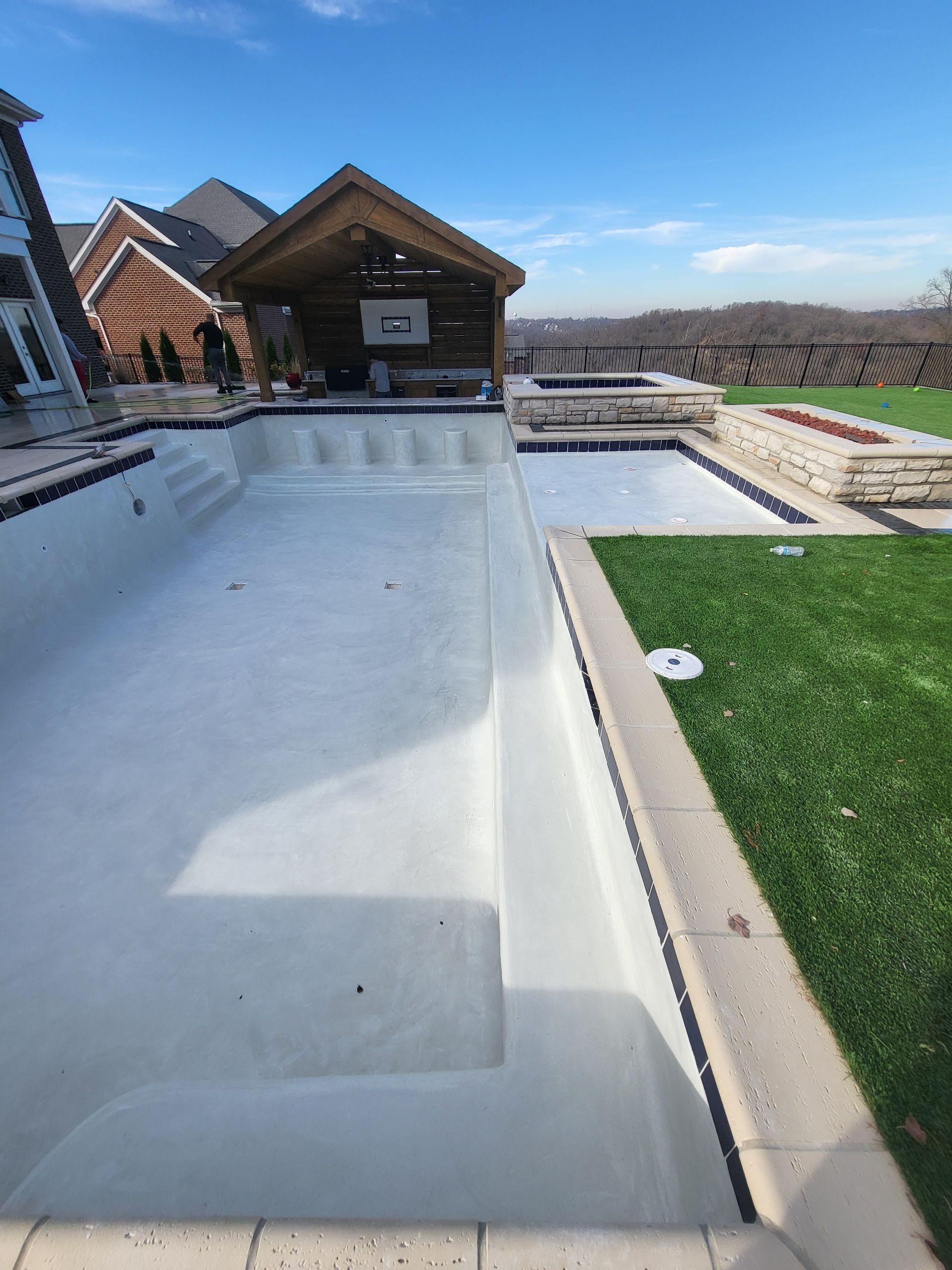 An empty swimming pool with a house in the background