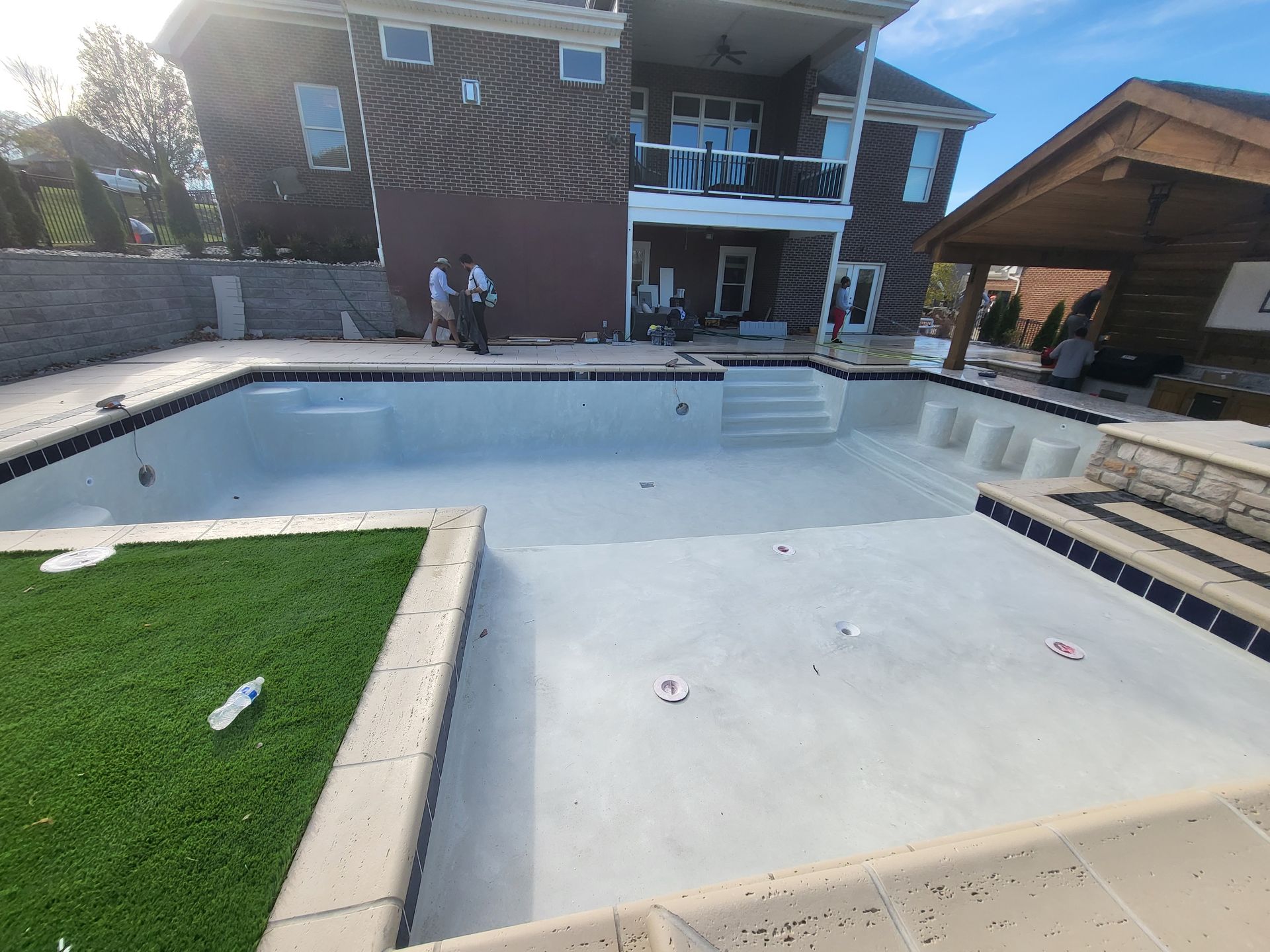 A large swimming pool is being built in the backyard of a house.
