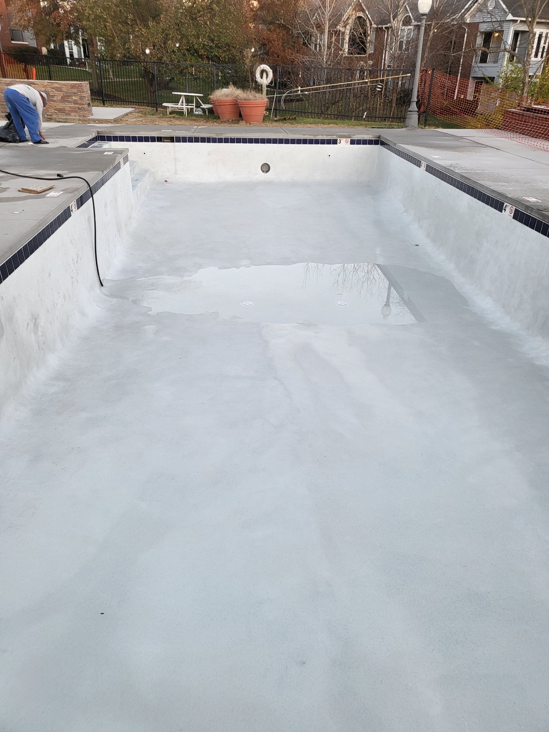 An empty swimming pool is being painted white.