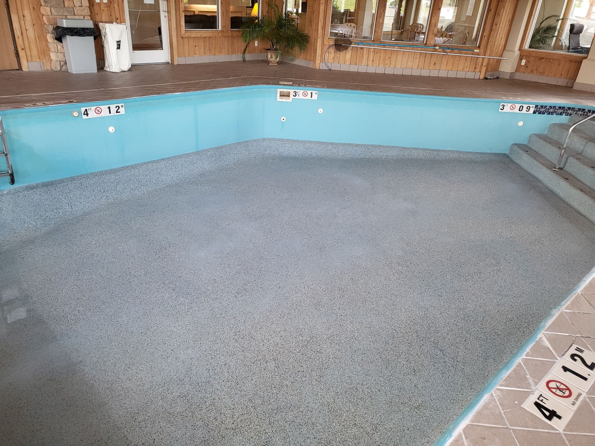 An empty swimming pool with a gray tile floor