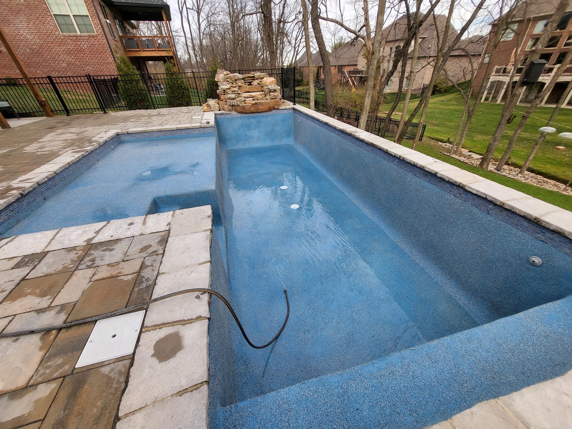 A large swimming pool with a hose attached to the side of it.
