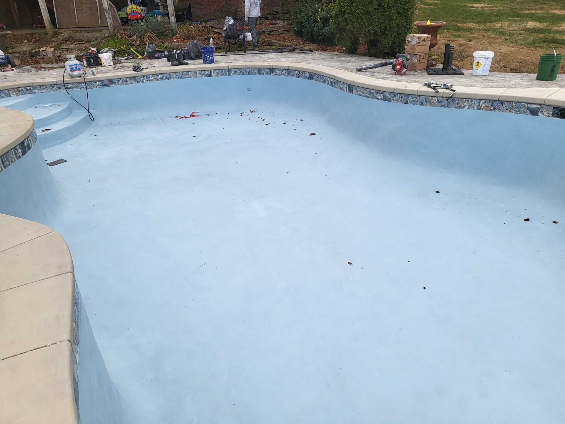 A large swimming pool is being painted blue.