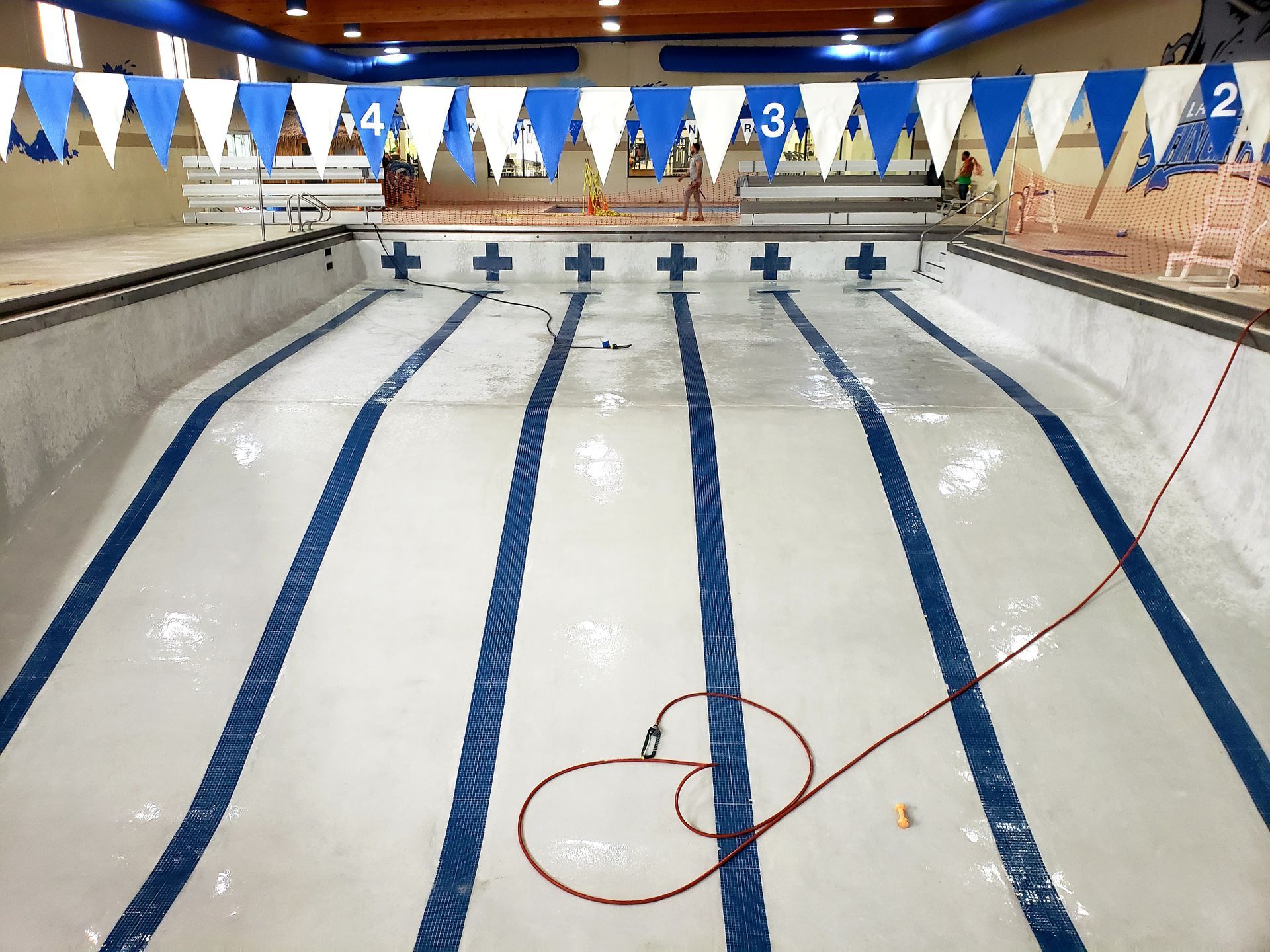 An empty swimming pool with blue and white flags hanging from the ceiling