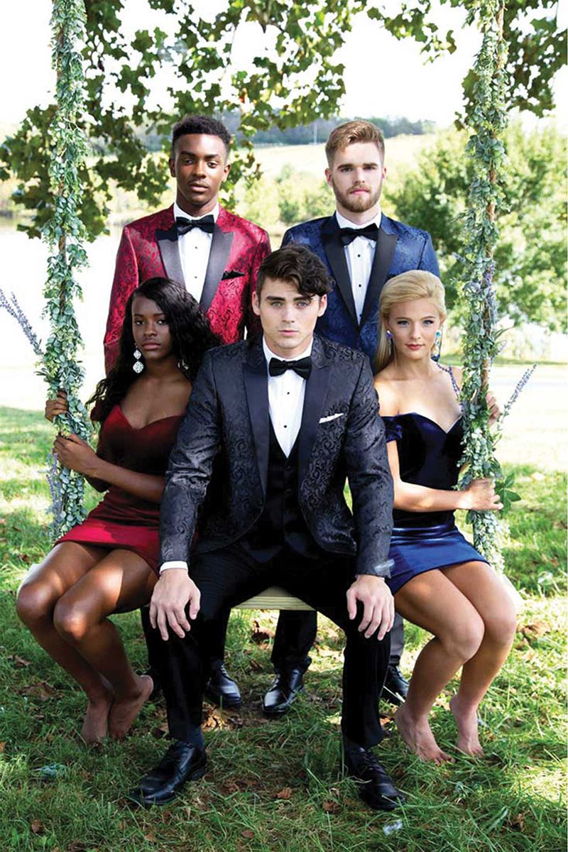 Three men in tuxedos are standing next to each other in front of a large window.