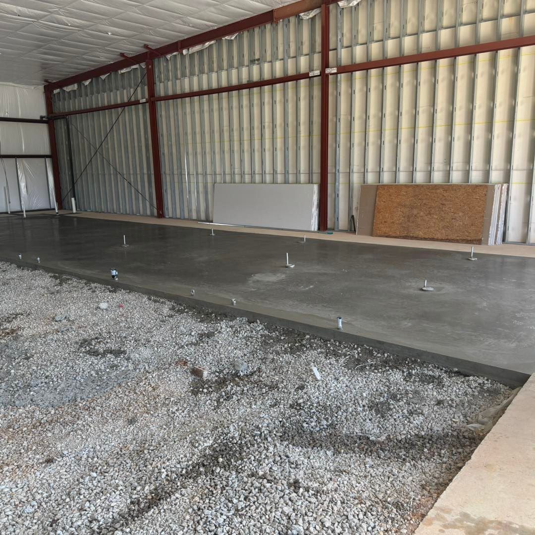 Empty metal warehouse interior with concrete floor and gravel foreground