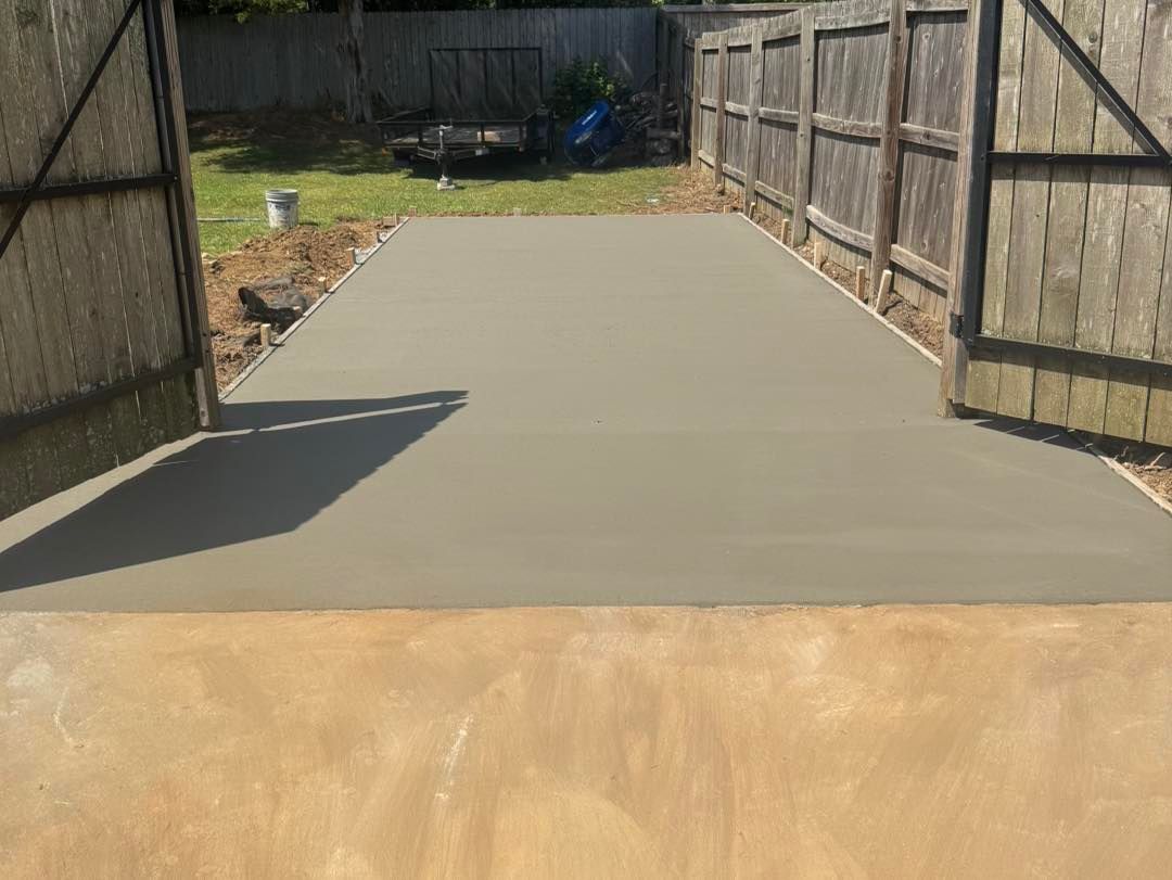 Freshly poured concrete patio or driveway between wooden fences in a backyard