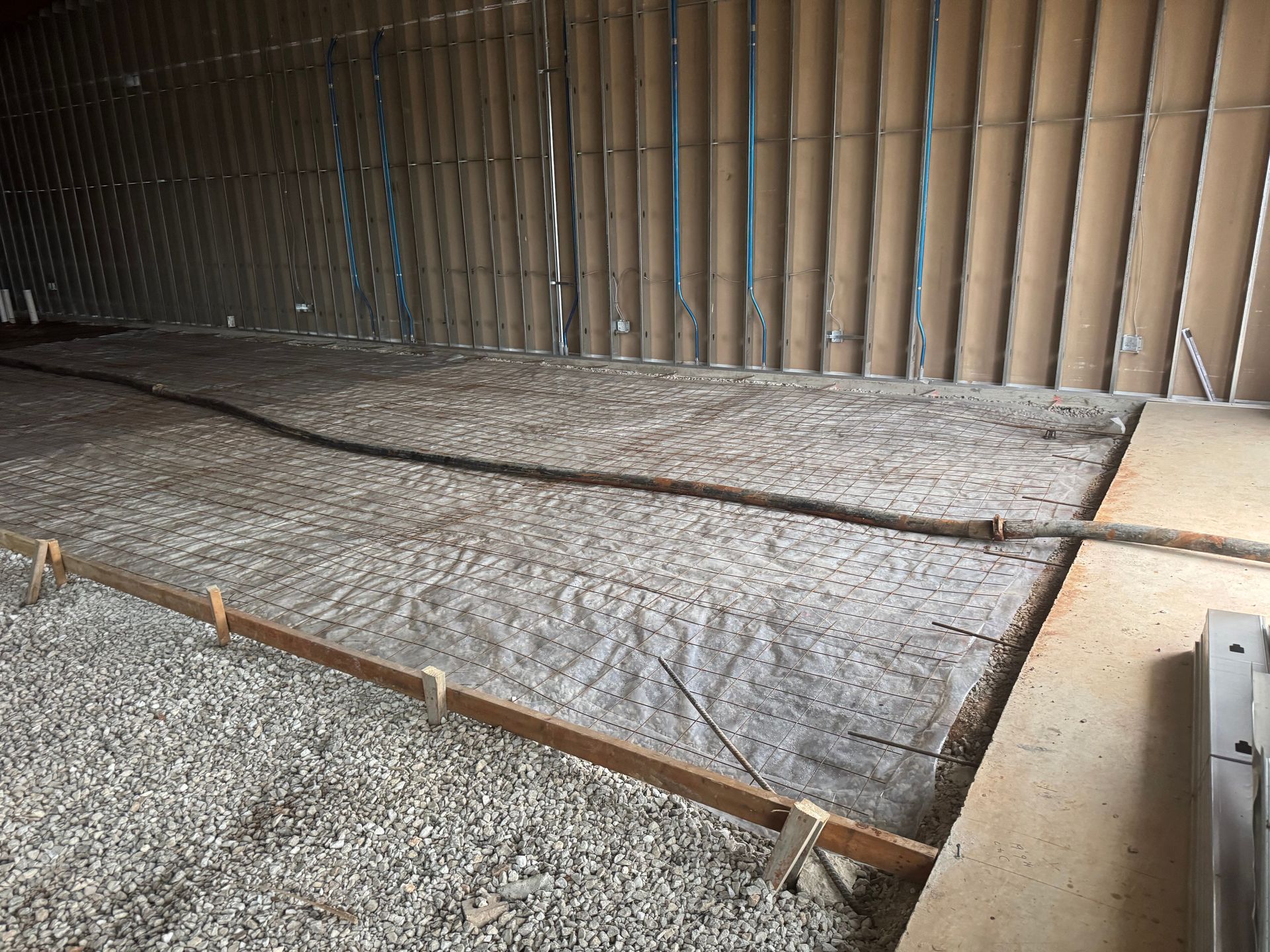 Gravel-filled construction area with a wooden fence and metal edging along the floor