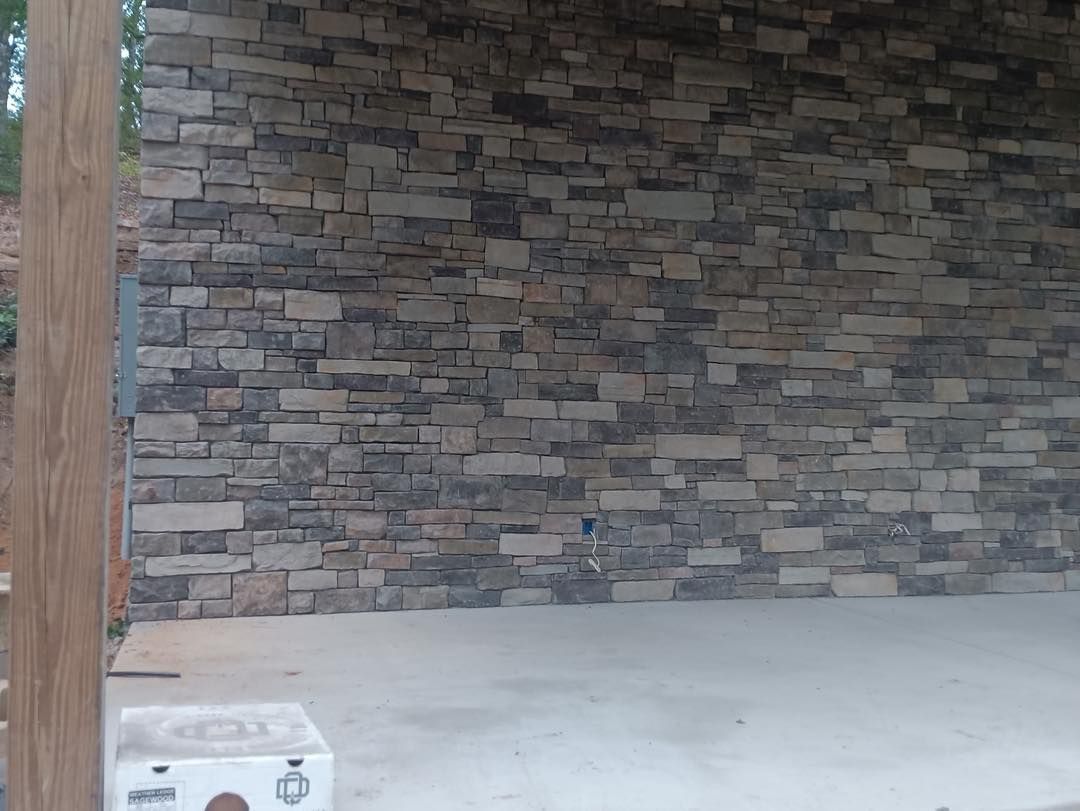 Empty room with stone accent wall, white floor, and a cardboard box in the corner
