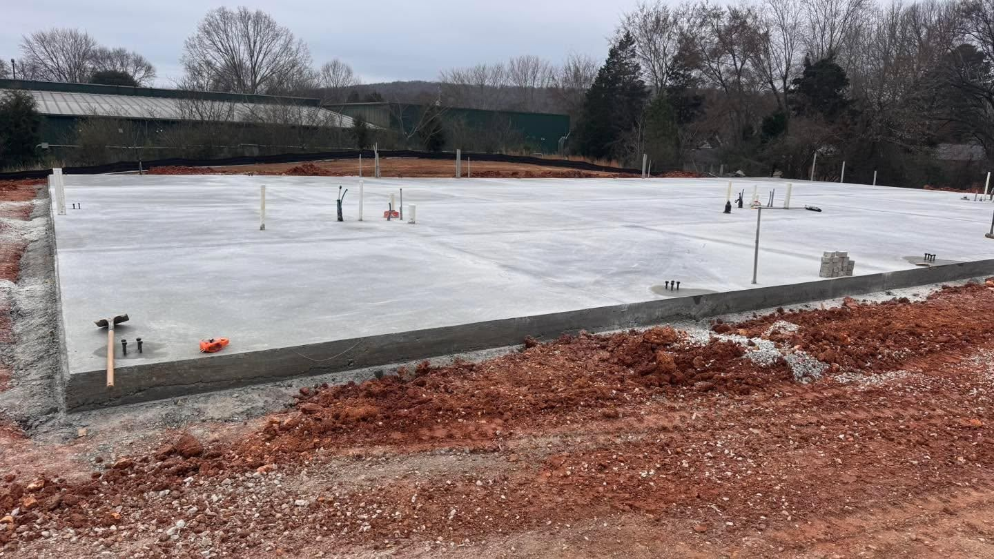 Concrete foundation slab at a construction site, with rebar and snowy ground around it