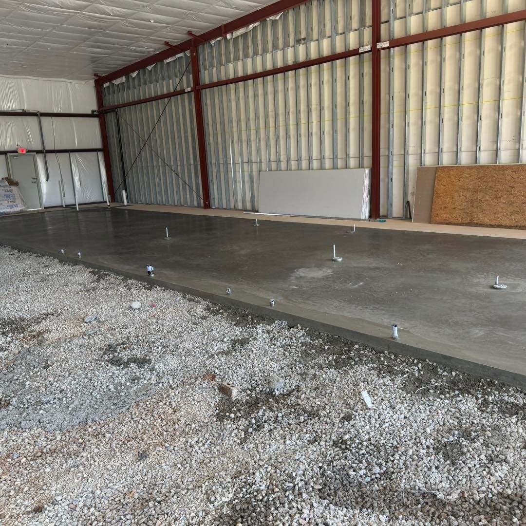 Empty warehouse interior with a new concrete slab and gravel foreground