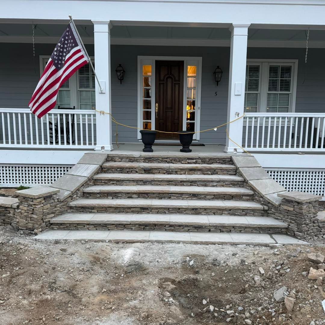 Front porch with American flag, steps, and double front doors on a gray house