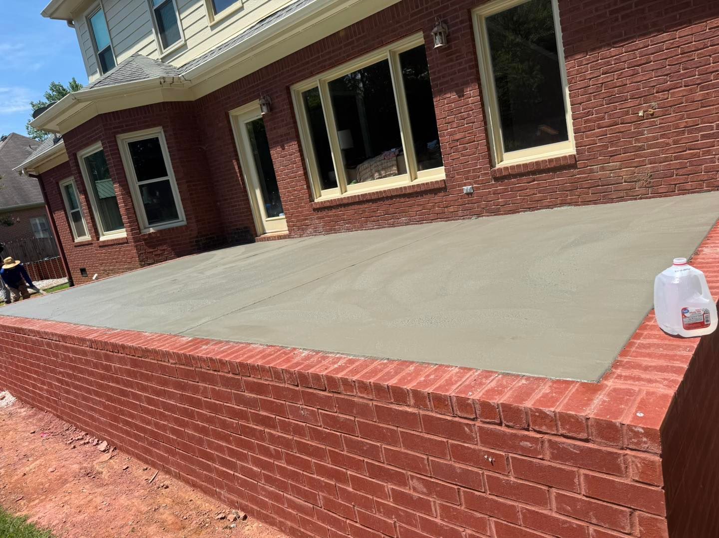Brick house with a large concrete porch and a water jug on the right side.