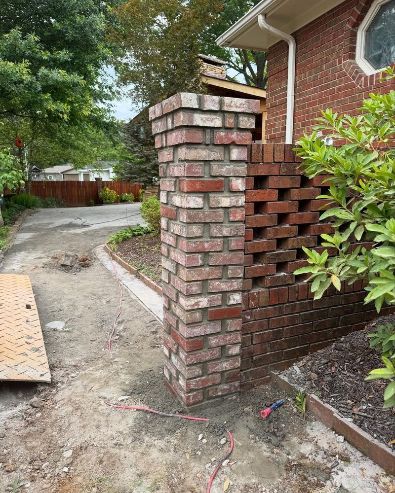 Brick gate pillar beside a curved driveway and brick wall in a residential yard