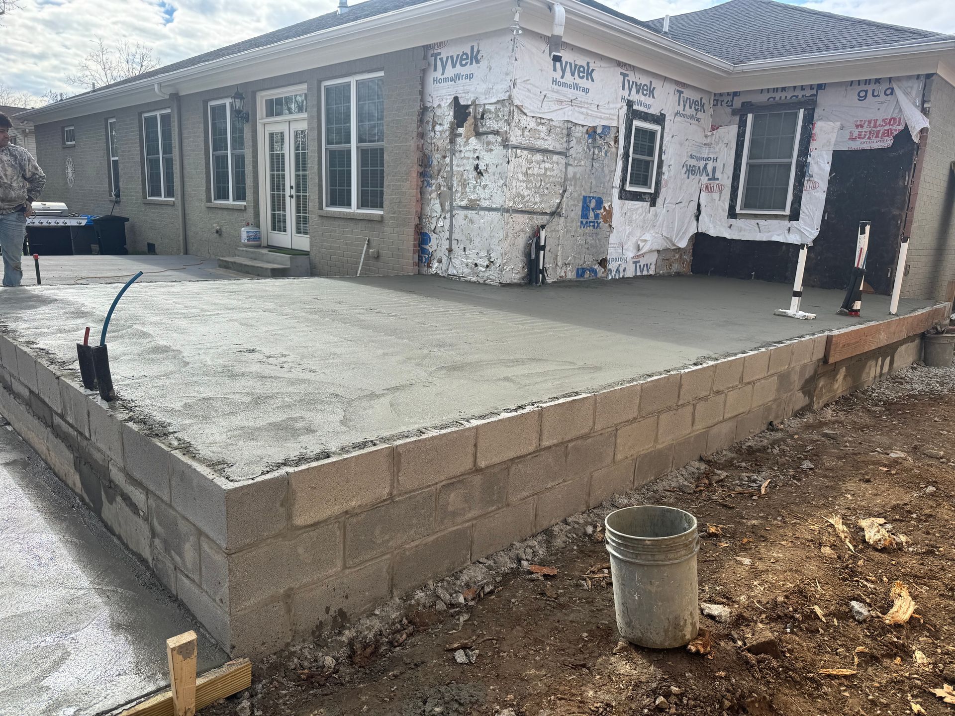 Partially built house with a concrete patio and low block retaining wall in front.
