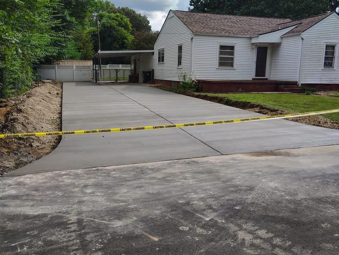 Concrete driveway with a yellow caution tape barrier beside a white house and landscaped yard