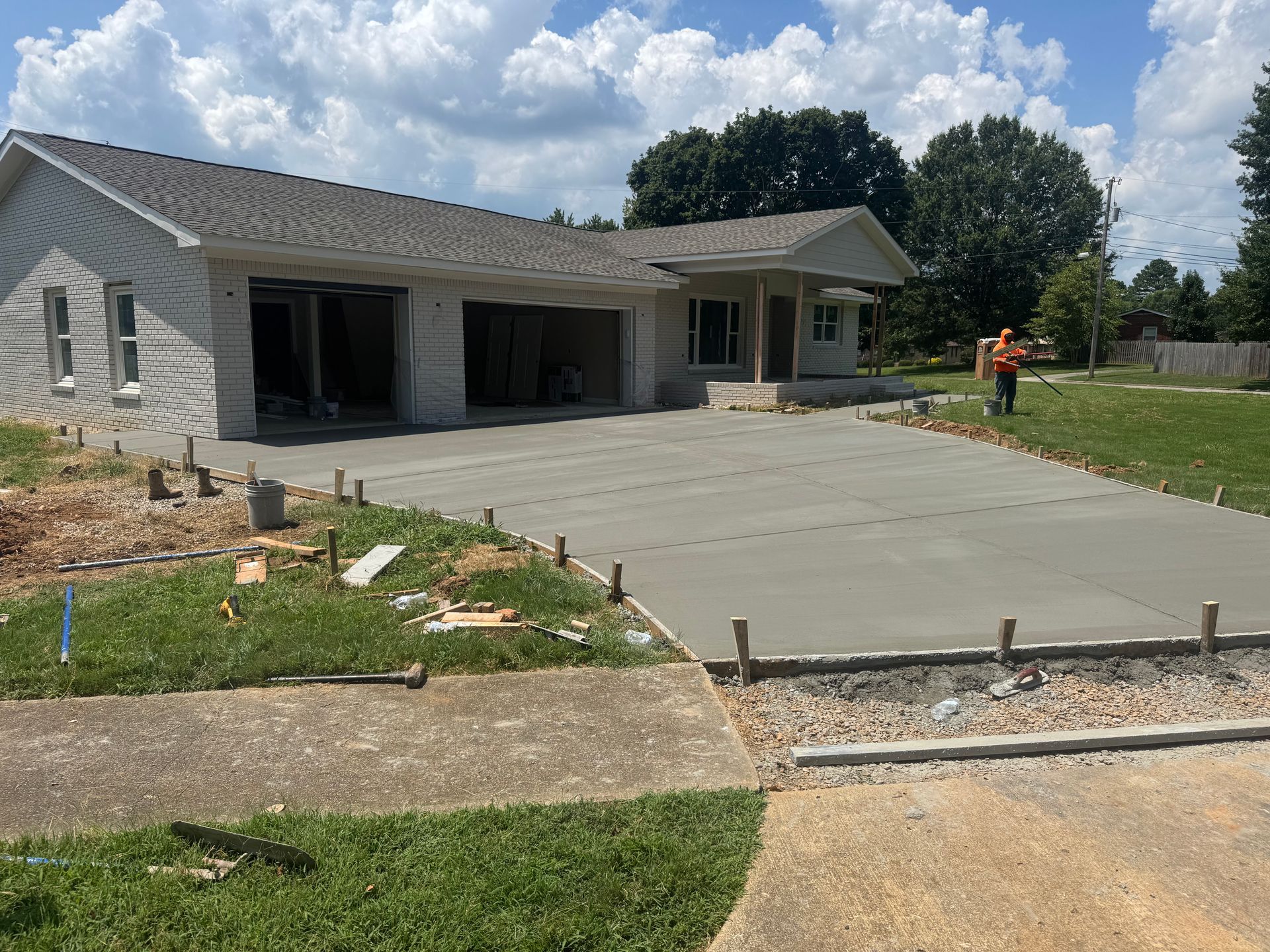 New house with a concrete driveway and a worker in an orange vest on the lawn