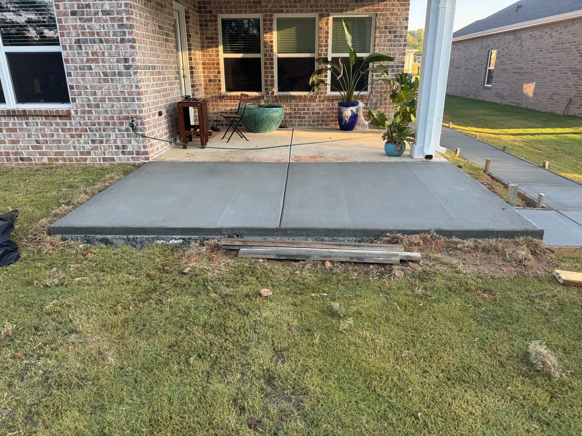 Front porch with a gray concrete ramp and steps leading to a brick house entrance.