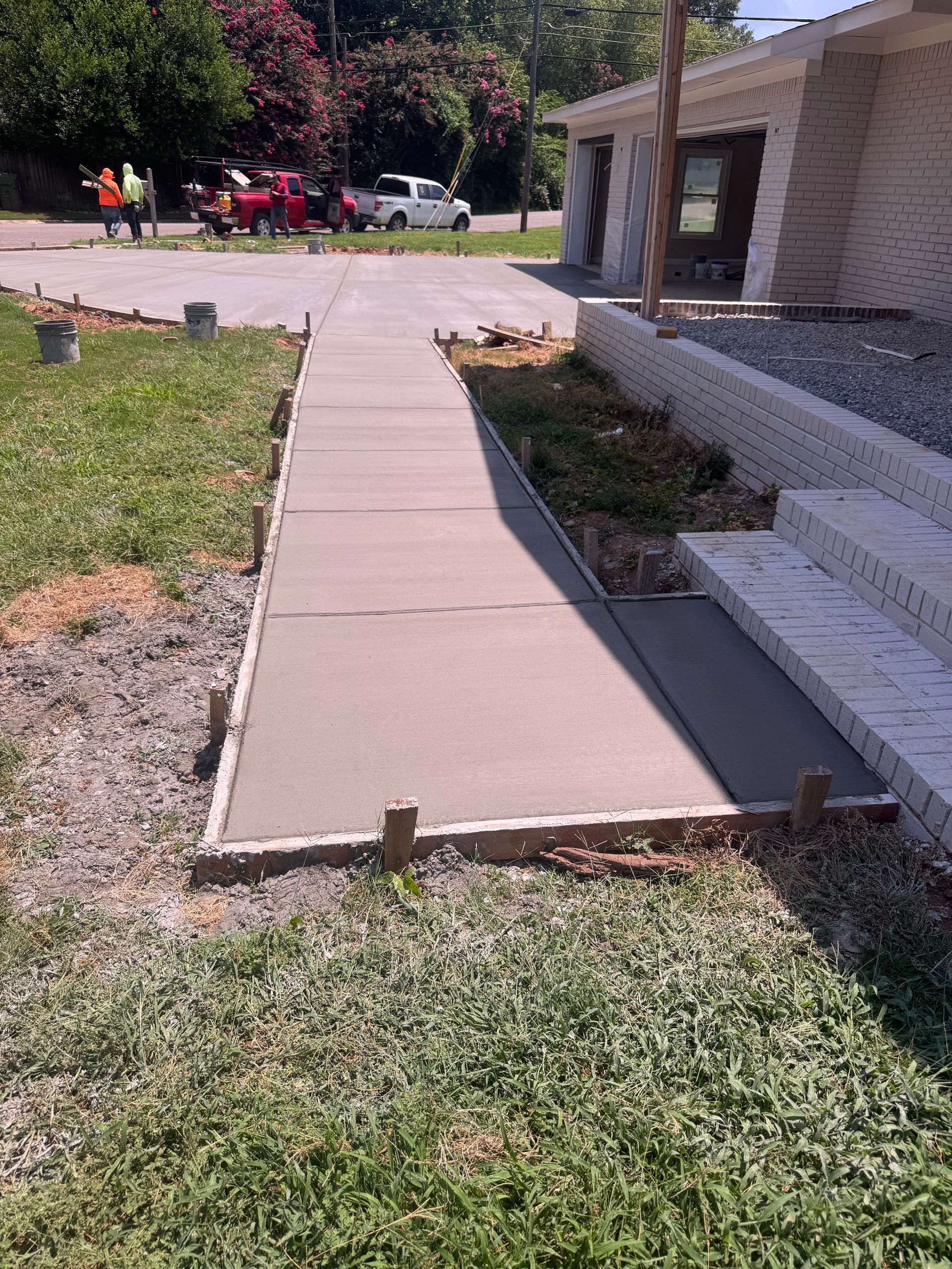 Concrete walkway leading to a building entrance beside a gravel and grass yard