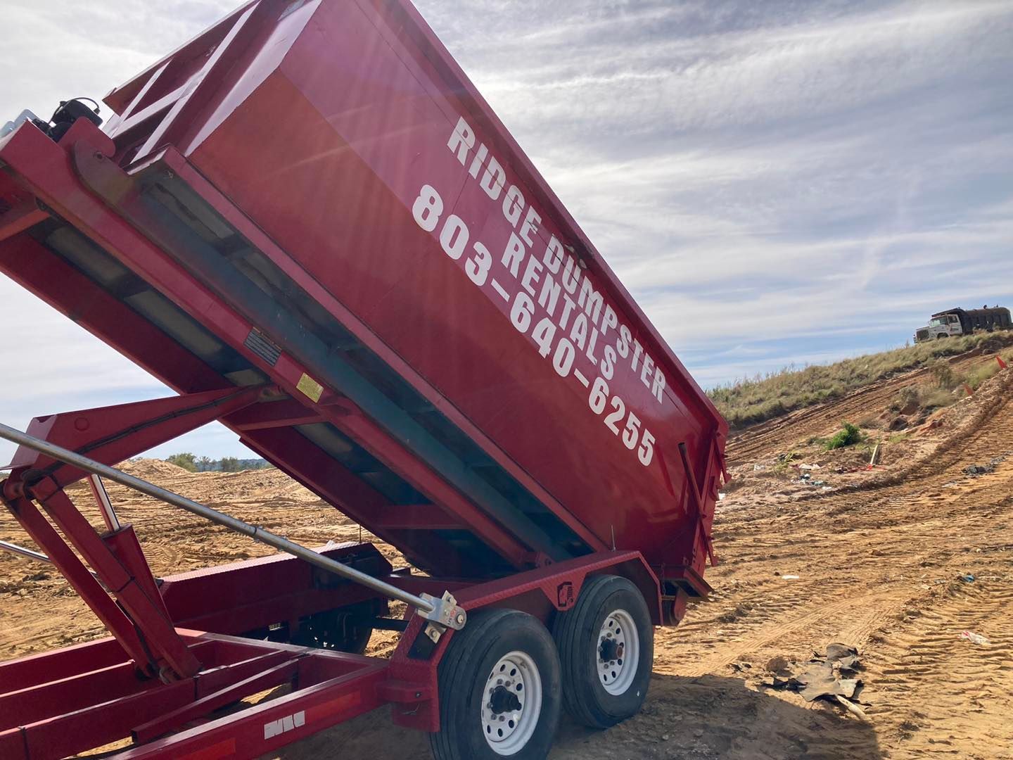 Red dumpster trailer with open bed,