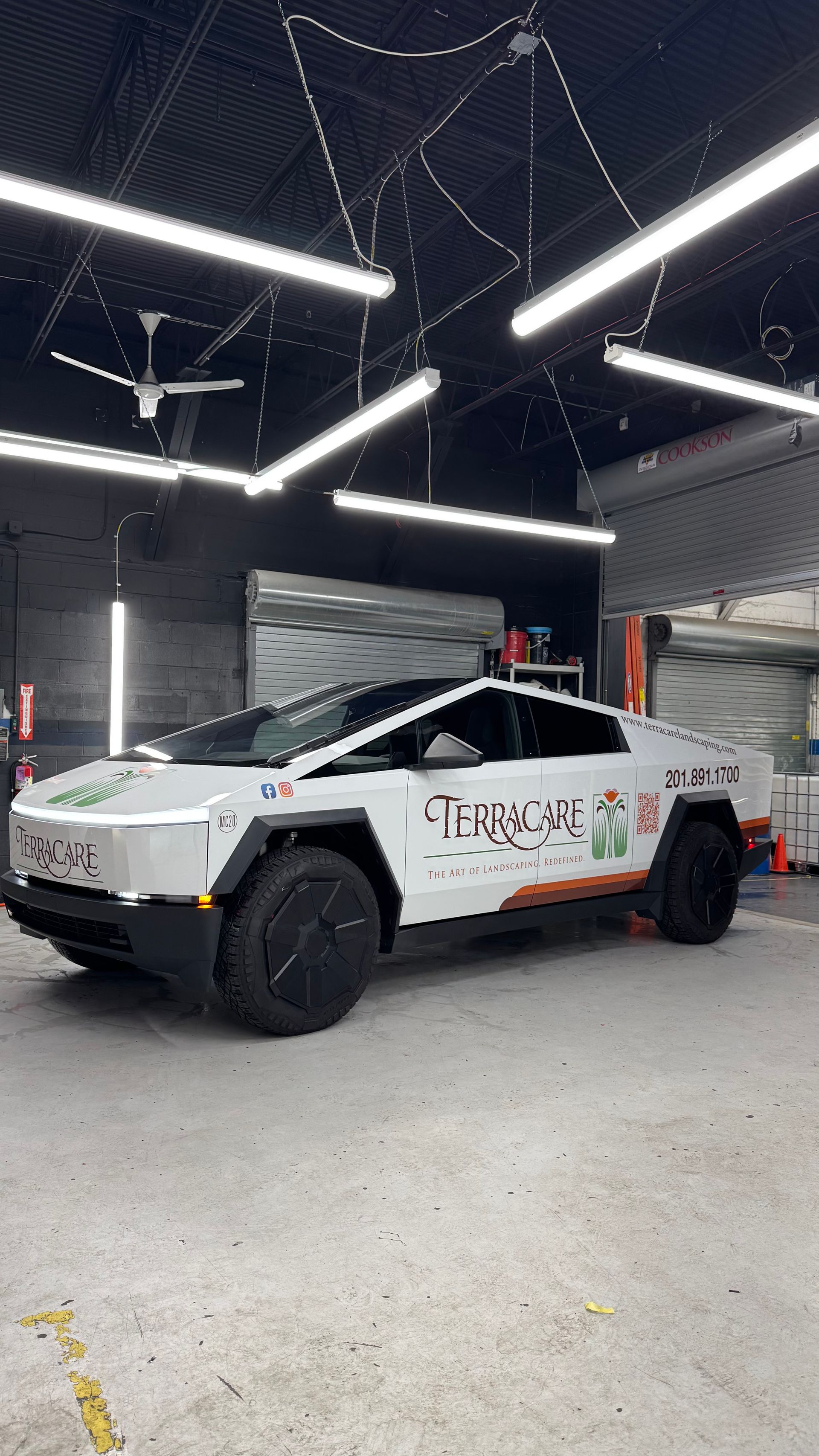 A white tesla cybertruck is parked in a garage.