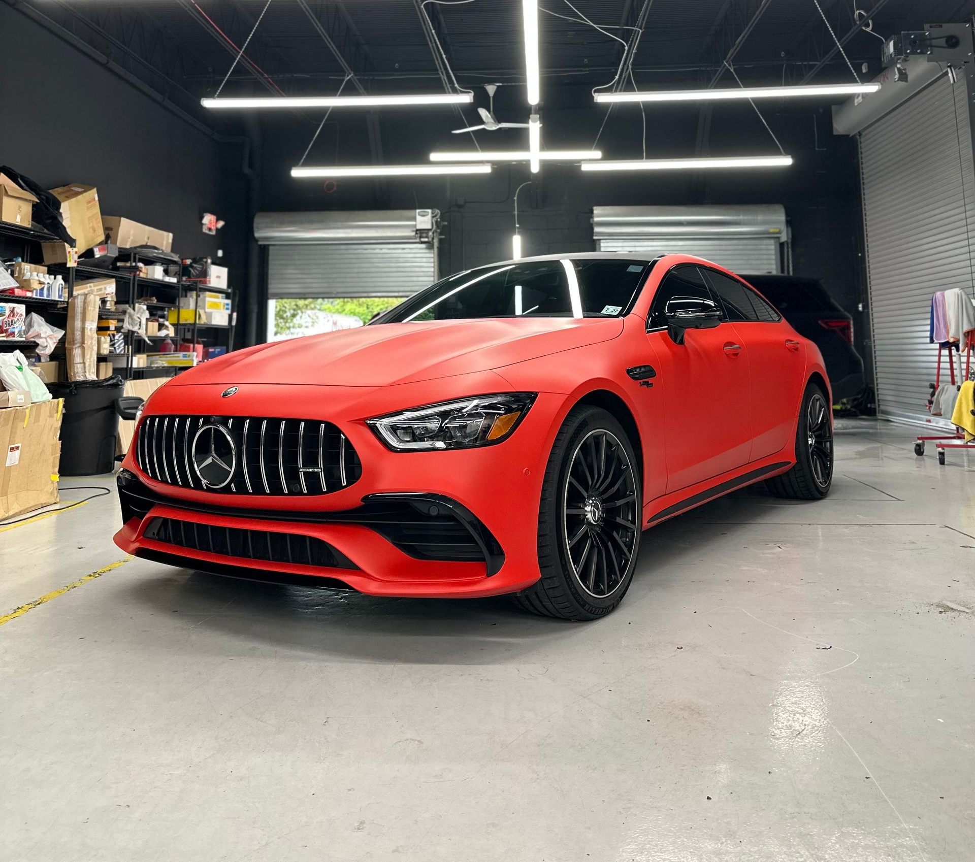 Red matte Mercedes-AMG GT four-door coupe parked inside a brightly lit garage.