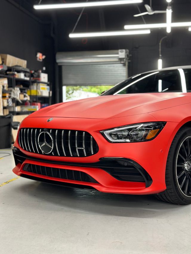 Red sports sedan with black grille in a garage, front view