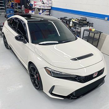 A white honda civic is parked in a garage.