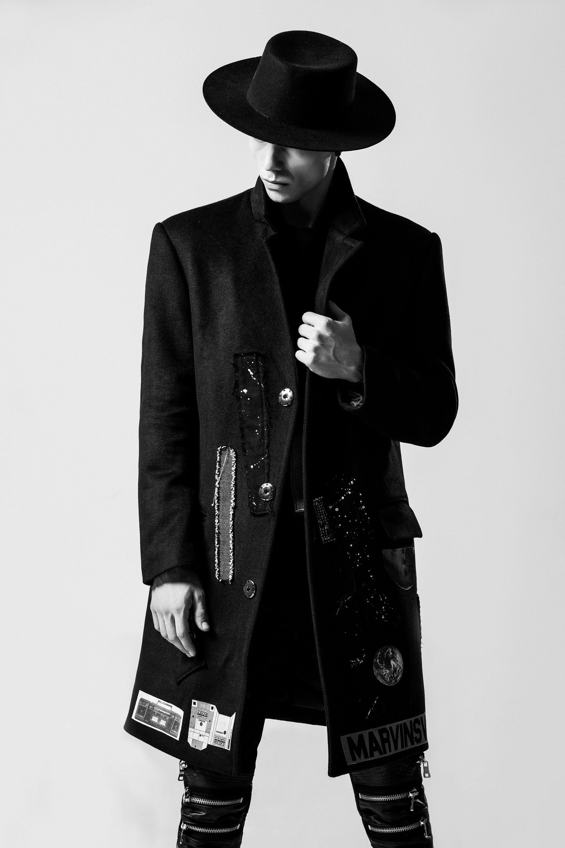 A black and white photo of a man wearing a hat and a coat