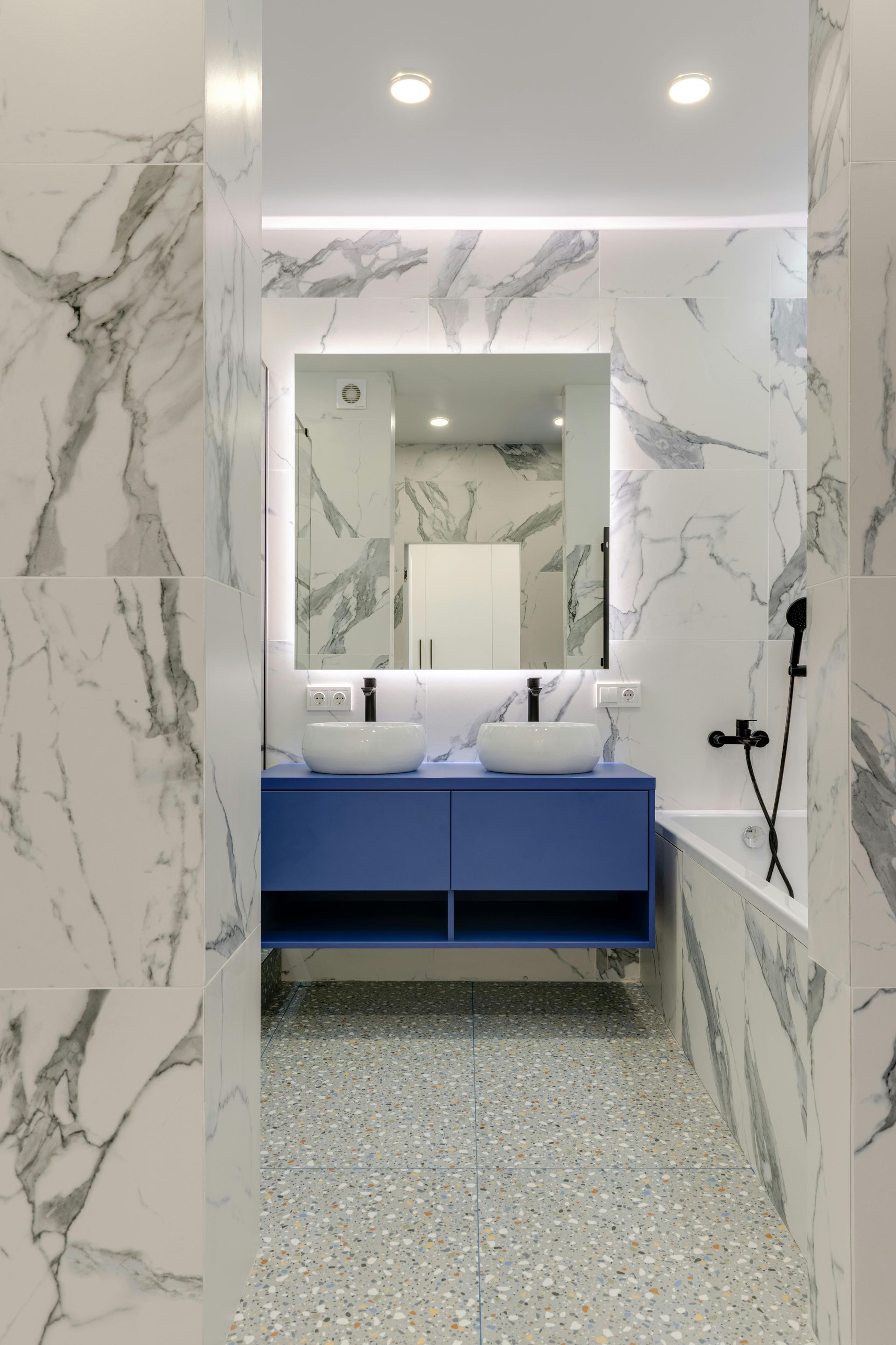 A bathroom with two sinks , a mirror and a bathtub.