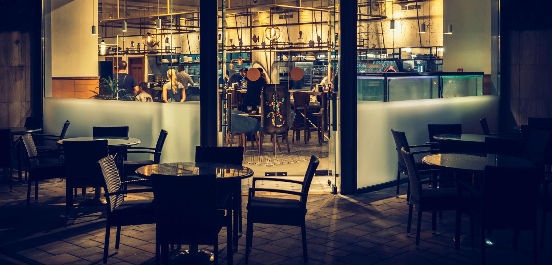 A restaurant with tables and chairs outside at night.