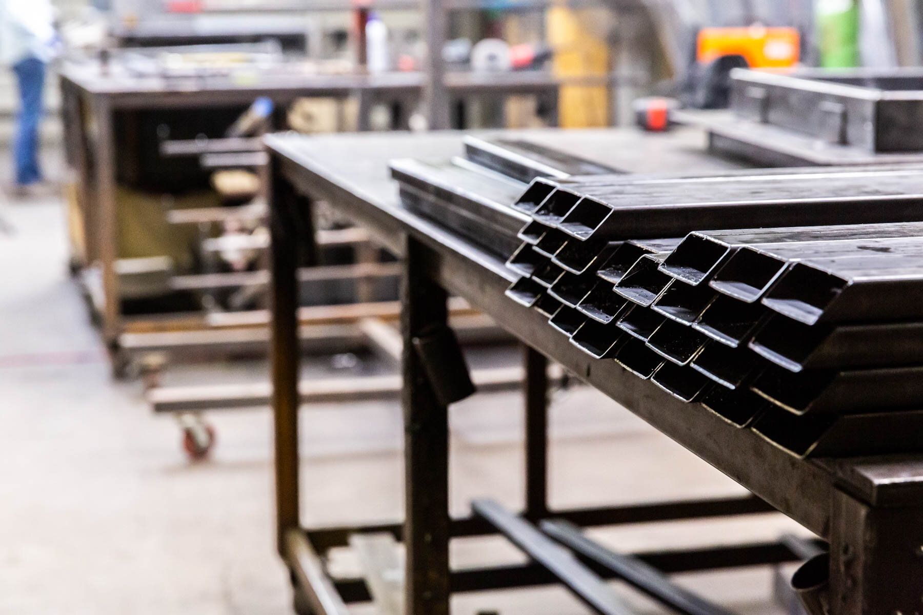 A stack of metal pipes sitting on top of a wooden table in a factory.